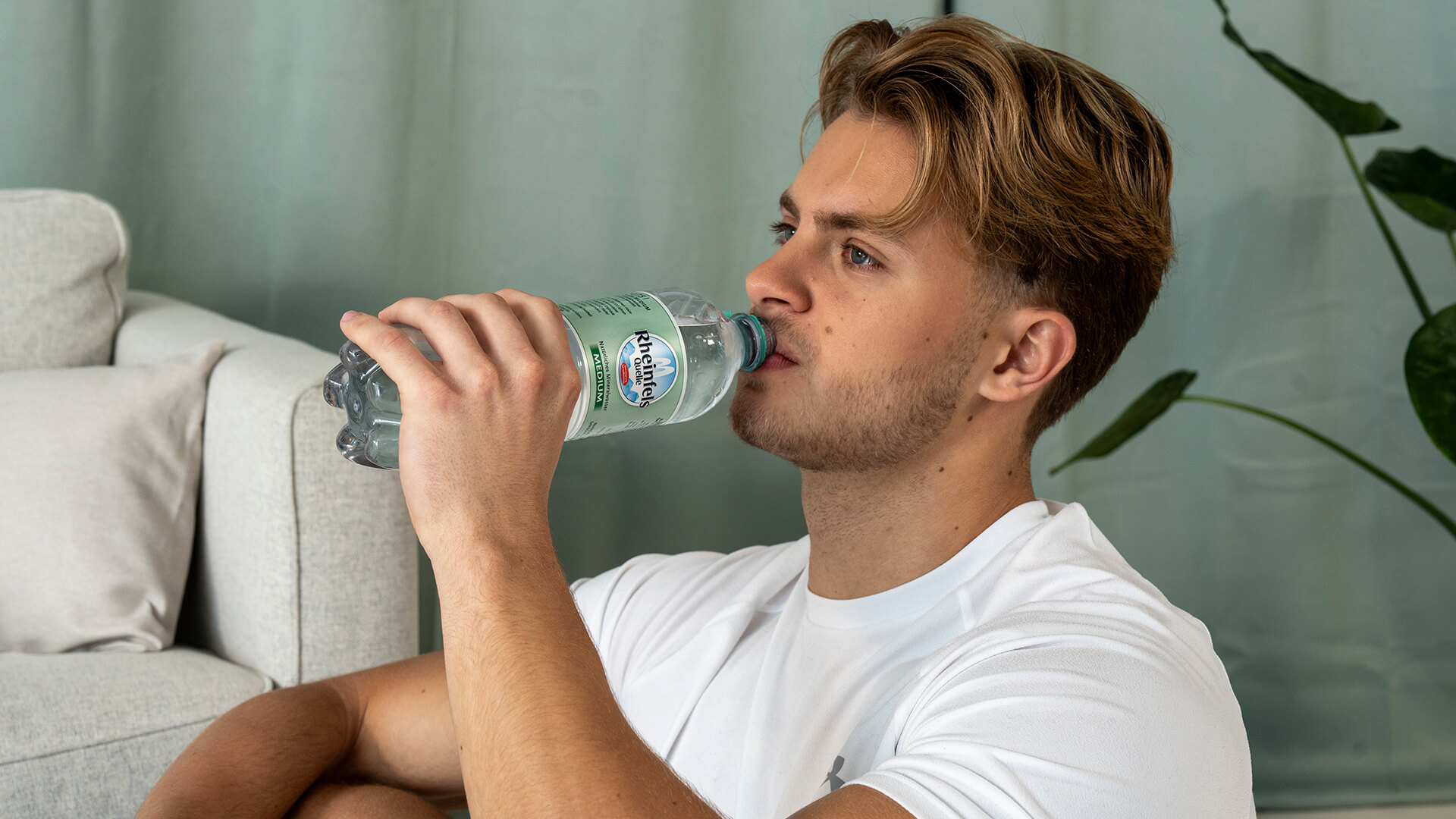 Junger Mann trinkt Rheinfels Medium aus der Flasche