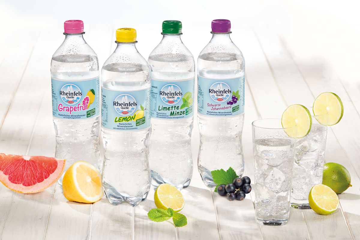 Bild von den Rheinfels Quelle Sorten Grapefruit, Lemon, Limette-Minze und Schwarze Johannisbeere, die nebeneinander auf einem Tisch stehen