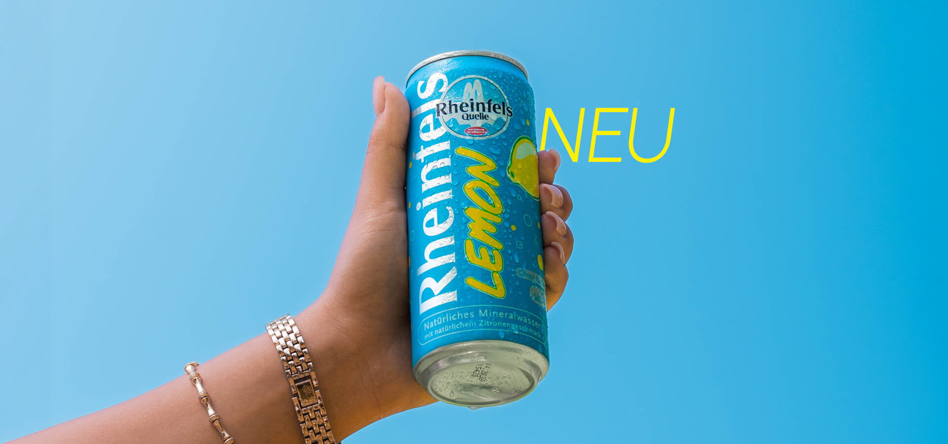 Eine gut gekühlte Dose Lemon, in der Hand vor strahlend blauen Himmel